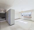 Empty room with windows and balcony, white walls, white ceiling, large storage cabinet, and a radiator