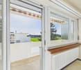 large glass windows, balcony, wooden floor, white walls, white heater