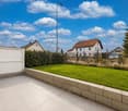 well-maintained garden with green lawn, stone wall, and a clear view of the neighborhood