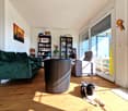 living room with green couch, round chair, gray armchair, bookshelves, sliding glass door, wooden floor, dog