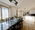 Dining room with a glass table, black chairs, white cabinets, and a window with a view