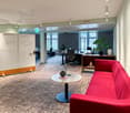 white board with Welcome message, modern office furniture, round table with books, office plants