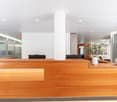 Large open lobby with wooden reception desk, glass walls, and modern decor including a plant and decorative objects