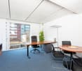 Spacious office with large windows providing a view, wooden desk, office chair, conference table, and potted plant