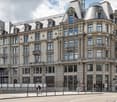 5 story building, multiple windows, balconies, modern architecture, grey exterior, street in front
