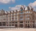 4 story building, brick facade, ornate balconies, large arched windows, red roofs, street facade