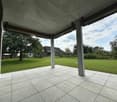 covered patio with tiled floor, wooden columns, open to grassy field