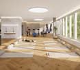 Large open space with hardwood floors, floor-to-ceiling windows, physiotherapy equipment such as exercise balls and suspension straps, and a sign indicating this is a physiotherapy room