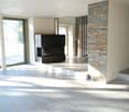 Spacious living room with large windows, hardwood flooring, and a stone fireplace feature wall