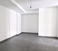 Empty room with white walls, gray tiles, and a ceiling light