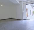 Empty room with white walls, gray tiles, open door, light fixture