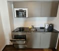 small compact kitchen, stainless steel appliances, microwave, dishwasher, black countertops, wooden floor