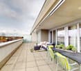 large balcony, white couch, table, chairs, plants, outdoor table, large windows, city view
