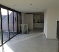 Empty room, white tiles, large glass doors, glass railing, white kitchen, white cabinets, white walls