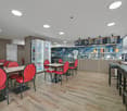 Wooden floor, red chairs, tables, counter, refrigerators, menu boards, stools