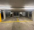 Underground parking garage with concrete floor, yellow parking space markings, and storage areas visible