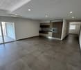Open-concept living space with a modern kitchen, hardwood floors, and recessed lighting. The room has a sliding glass door leading to an outdoor area.