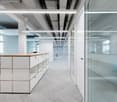 modern office space, white walls, glass doors, white cabinets, gray carpet, white ceiling lights