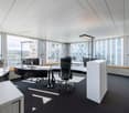 modern office with large windows, desks, chairs, monitors, lamps, carpeted floor
