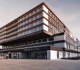Modern office building, multiple floors, glass windows, entrance with glass doors, name board 'AMBASSADOR HOUSE', parking area in front