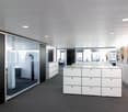 modern office space with glass walls, white cabinets, gray carpet, white ceiling, paintings on the wall