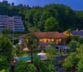 villa with brown roof, balcony, swimming pool, surrounded by lush greenery, mountain view