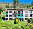 3 story house, white exterior, green balconies, large garden, trees, driveway