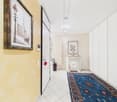 tiled floor, yellow wall, white door, picture frame, rug, cabinet, umbrella stand, radiator