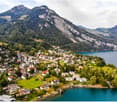 Aerial view of a village with many houses, surrounded by mountains and a lake