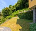 green lawn, stone wall, plants, trees, yellow house, view of the mountains