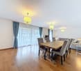 Dining room with wooden floor, large windows, chandeliers, dining table, chairs, couch, side table, lamp