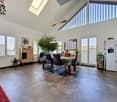 Dining room with large windows, wooden table, chairs, plants, wooden cabinet, refrigerator, tiled floor, skylight