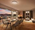 Dining room with large windows, wooden floor, table, chairs, lamps, couch, coffee table, rug, picture frame, balcony with outdoor furniture