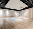 large open space, hardwood flooring, white walls, ceiling spotlights, undecorated room, doors and an open door at the back of the room.