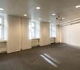 Empty room with large windows, radiators, ceiling lamps, projector