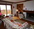 Cozy living room with floral patterned sofa, wooden furniture, fireplace, and access to a balcony or terrace through large windows