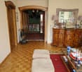 Wood floor, wooden door, hallway, two lamps, coffee table, sofa, rug, mirror, sideboard, picture frames