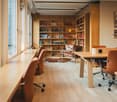 modern interior with wooden desks, chairs, bookshelves, glass windows, wooden flooring