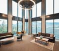 large windows, round chandelier, leather sofas, wooden coffee tables, desk, chair, rug