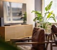 living room, flat screen TV, entertainment center, plant, brown leather chairs, game controller