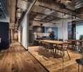 open office plan, wooden floors, glass walls, metal beams, central kitchen, dining tables, plants