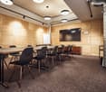 conference room with long table, black chairs, wooden walls, mounted television