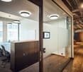 Long table, chairs, metal cabinets, glass walls, monitor on wall