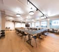 Meeting room, long tables, U-shaped seating, whiteboard, windows with city view, track lighting