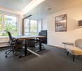 Office room with two desks, office chairs, small chair, standing lamp, picture frame, window