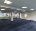 Empty room, carpeted floor, white walls, recessed ceiling lights, two round windows
