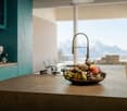 kitchen with island, teal cabinets, granite countertop, gas stove, faucet, bowl of fruit, large windows, view of mountains