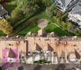 Complex with many buildings, large garden, circular driveway, brown roof, windows, parking lot