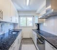 modern kitchen with granite countertops, stainless steel appliances, white cabinets, double sink, induction cooktop, dishwasher, and a window with a view