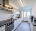 modern kitchen with granite countertops, stainless steel appliances, white cabinets, and a window with a view
